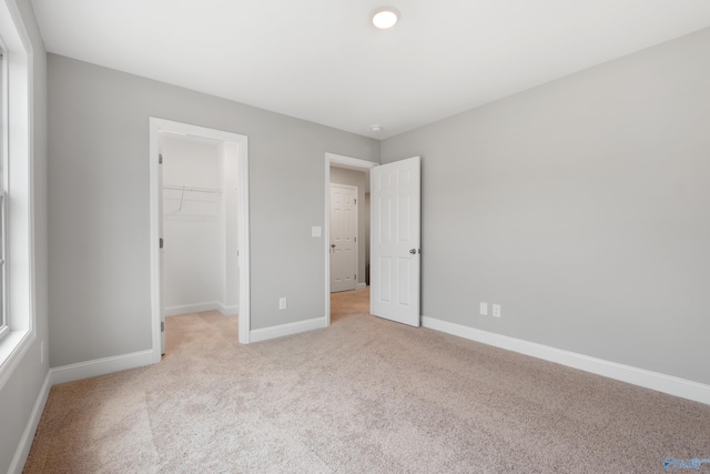 120 Burdine St, New Market, AL 35761 - unfurnished bedroom with baseboards, a closet, a walk in closet, and light colored carpet