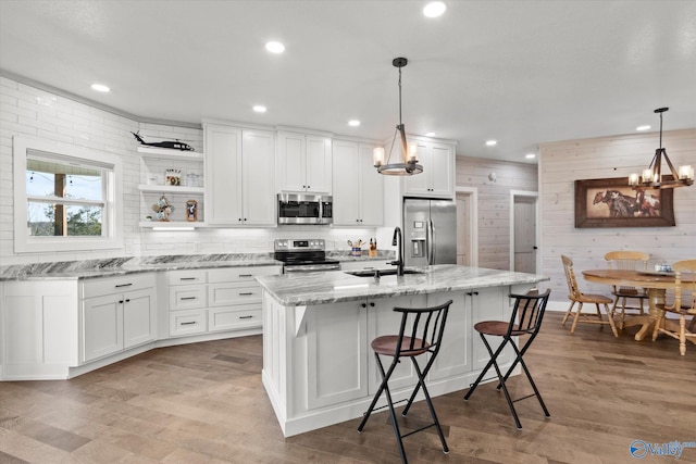 kitchen featuring sink, stainless steel appliances, white cabinetry, and pendant lighting