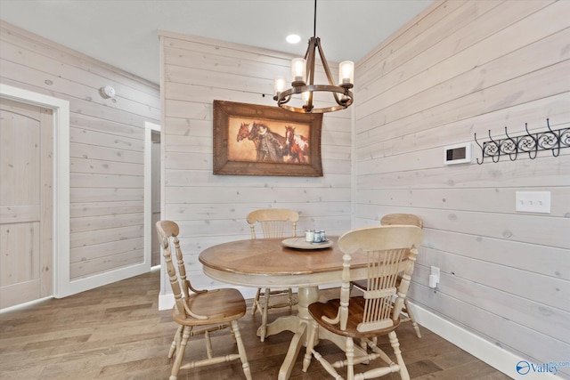 dining space featuring an inviting chandelier, wood walls, and hardwood / wood-style floors