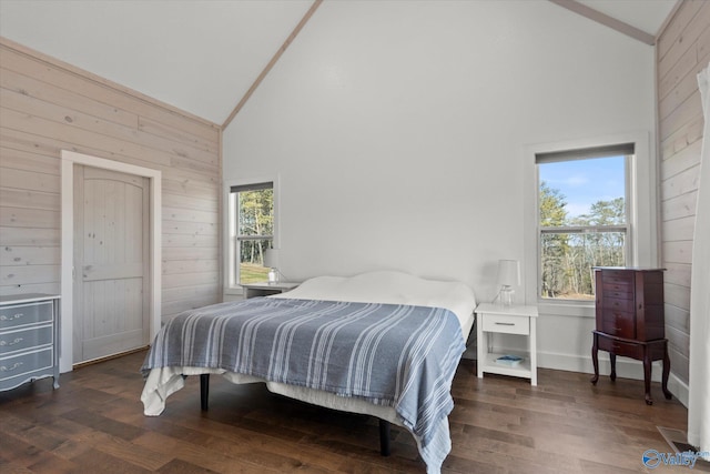 bedroom with high vaulted ceiling, wood walls, and dark wood-type flooring