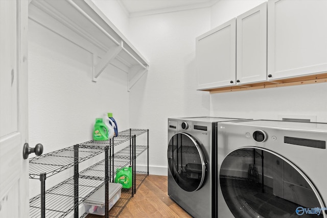 laundry room with washer and dryer, cabinets, and light hardwood / wood-style flooring