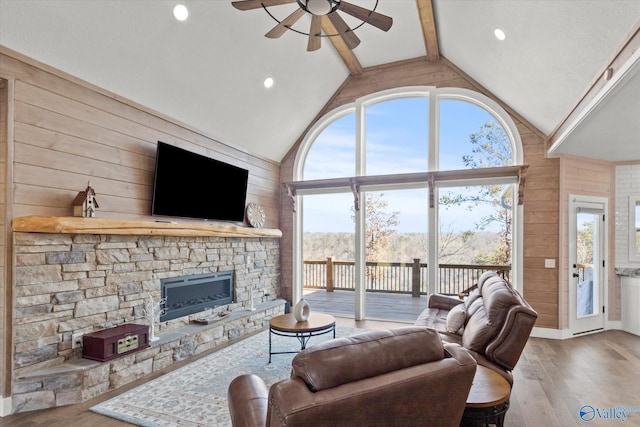 living room featuring wood walls, hardwood / wood-style floors, high vaulted ceiling, beam ceiling, and ceiling fan