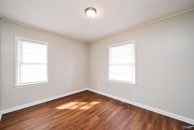 empty room featuring visible vents, a healthy amount of sunlight, baseboards, and wood finished floors