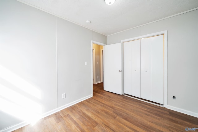unfurnished bedroom with crown molding, baseboards, and wood finished floors