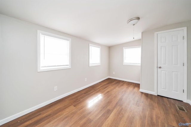 unfurnished bedroom featuring vaulted ceiling, wood finished floors, visible vents, and baseboards