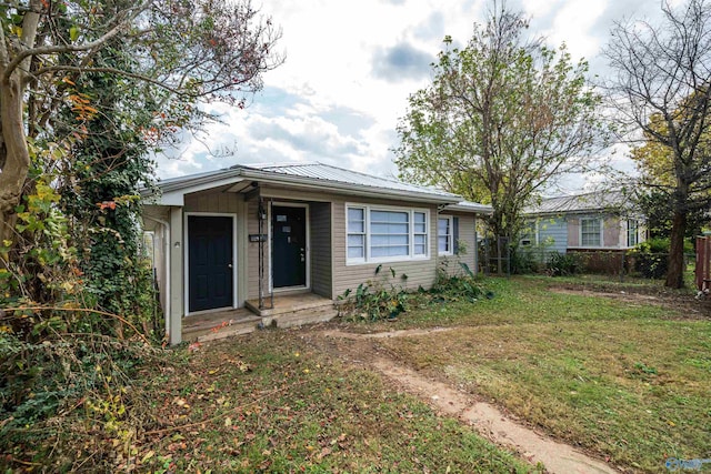 view of front of property featuring a front lawn, fence, and metal roof