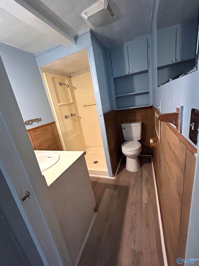 bathroom featuring vanity, a shower, hardwood / wood-style floors, and toilet