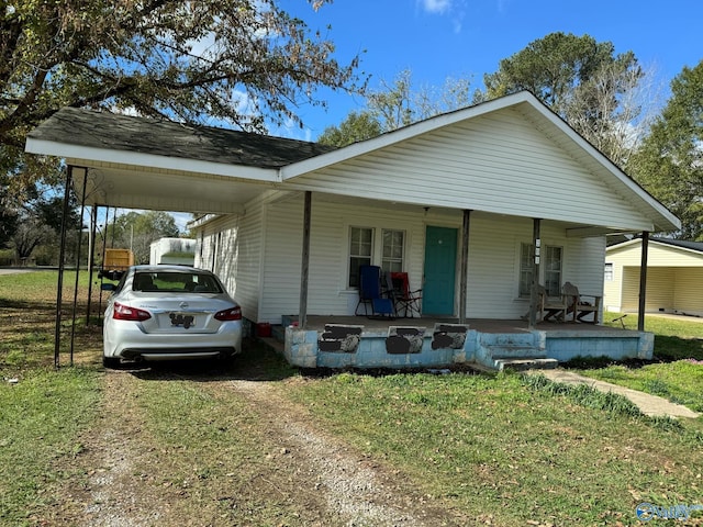 view of front of property featuring a front lawn, covered porch, and a carport