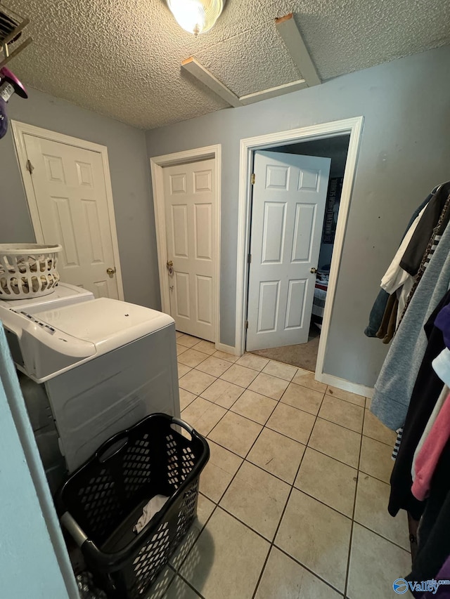 laundry area with light tile patterned floors, a textured ceiling, and separate washer and dryer