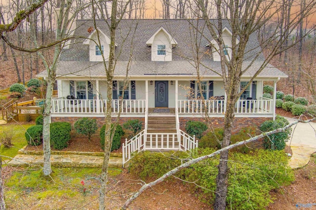 cape cod-style house featuring a porch, stucco siding, a shingled roof, and stairs