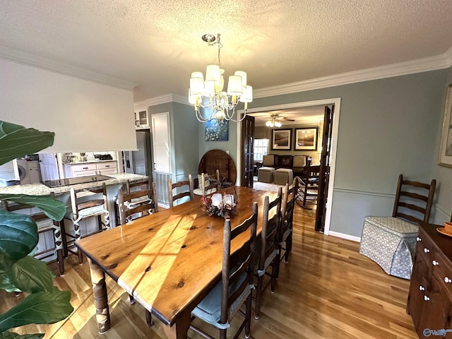 dining room featuring a textured ceiling, ornamental molding, wood finished floors, and ceiling fan with notable chandelier