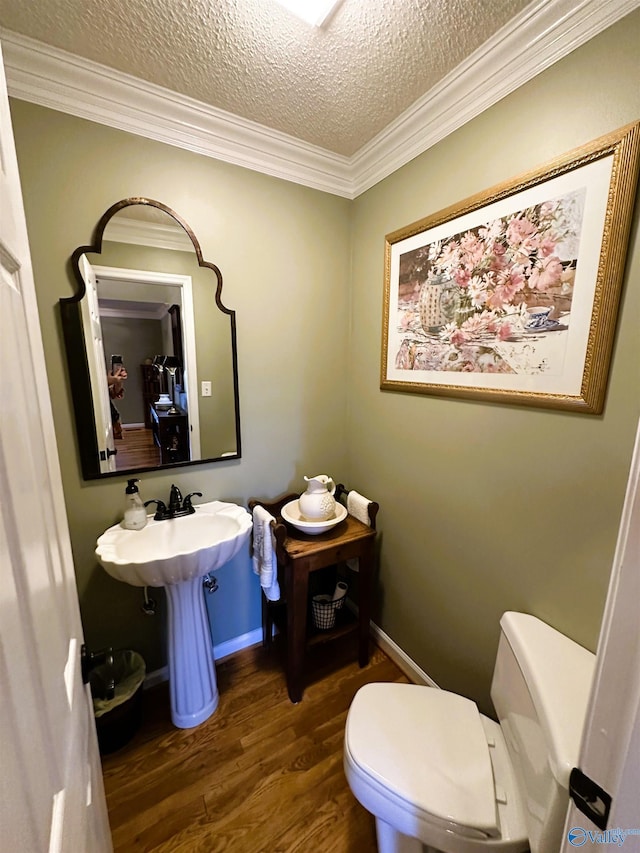 half bath with crown molding, toilet, a textured ceiling, wood finished floors, and baseboards