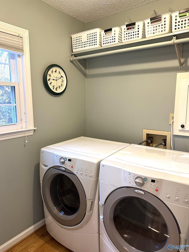 washroom with a textured ceiling, laundry area, wood finished floors, baseboards, and washer and clothes dryer