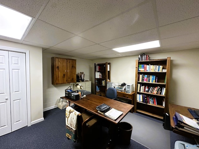 office featuring a paneled ceiling, baseboards, and dark colored carpet