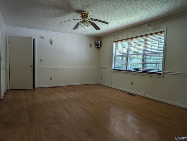 spare room with ceiling fan, a textured ceiling, wood-type flooring, and ornamental molding