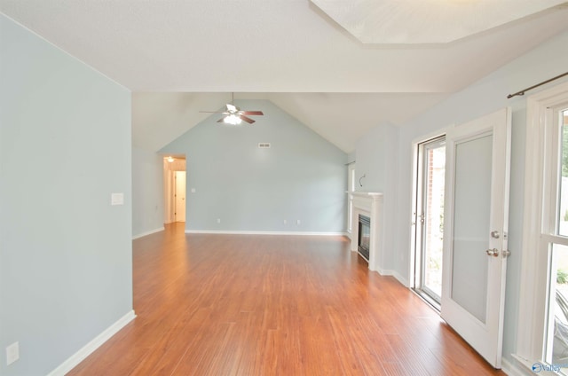 1422 Lake Crest Dr SW, Decatur, AL 35603 - unfurnished living room with light wood-type flooring, healthy amount of natural light, a glass covered fireplace, a ceiling fan, and vaulted ceiling