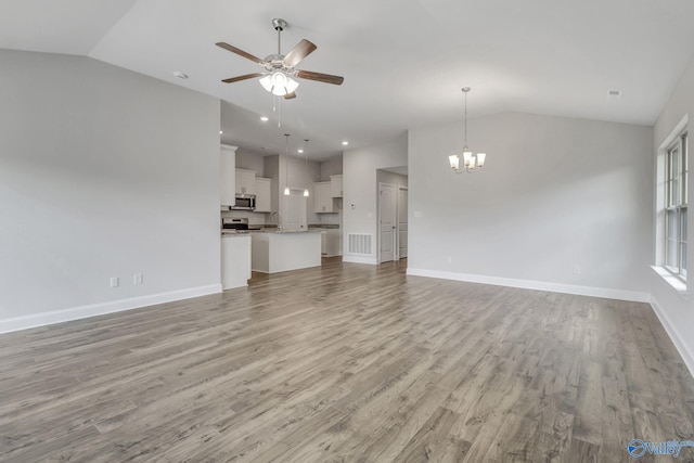 unfurnished living room featuring lofted ceiling, ceiling fan with notable chandelier, baseboards, and light wood finished floors