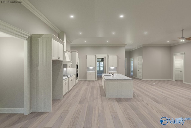 kitchen with white cabinetry, ceiling fan, stainless steel gas cooktop, a kitchen island with sink, and light wood-type flooring