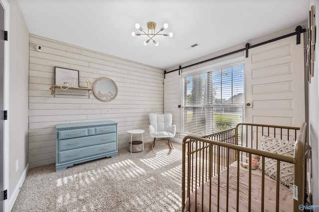 119 Saint Clair Ln, Huntsville, AL 35811 - bedroom with a barn door, carpet, wood walls, and a nursery area