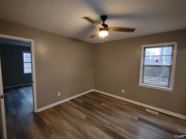 unfurnished room featuring a ceiling fan, dark wood-style flooring, visible vents, and baseboards