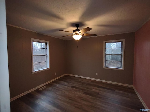 spare room featuring dark wood-style flooring, visible vents, ornamental molding, a textured ceiling, and baseboards