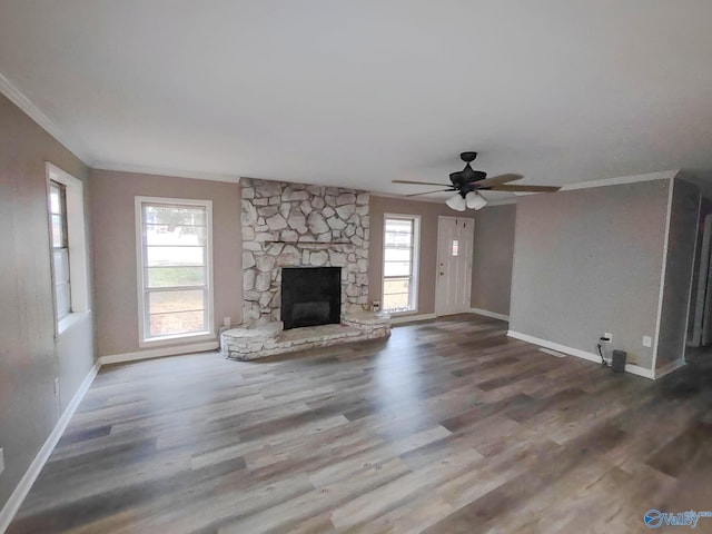 unfurnished living room with plenty of natural light, ornamental molding, a fireplace, and wood finished floors