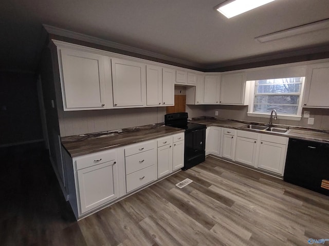 kitchen featuring wood finished floors, a sink, white cabinetry, black appliances, and dark countertops