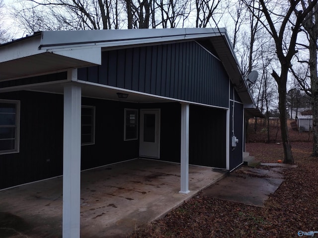 exterior space with board and batten siding and an attached carport