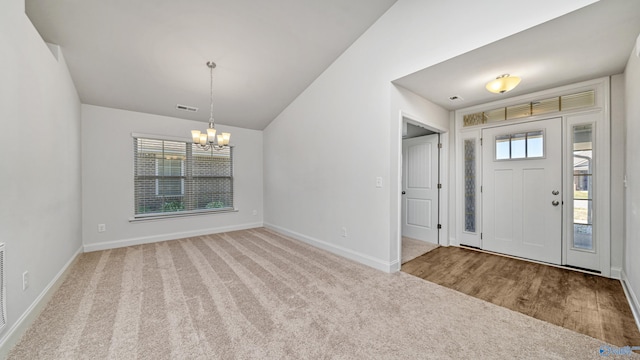 foyer entrance with carpet, a chandelier, and vaulted ceiling