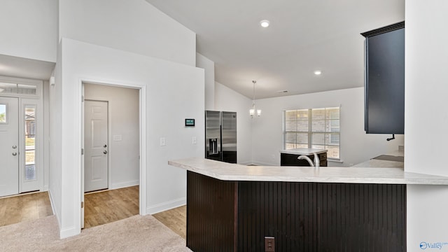 kitchen with stainless steel fridge with ice dispenser, light hardwood / wood-style flooring, kitchen peninsula, lofted ceiling, and a breakfast bar