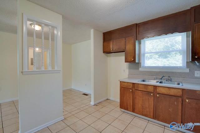 kitchen featuring a textured ceiling, sink, and light tile patterned floors