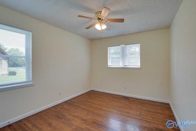 spare room with ceiling fan, a textured ceiling, wood-type flooring, and a wealth of natural light