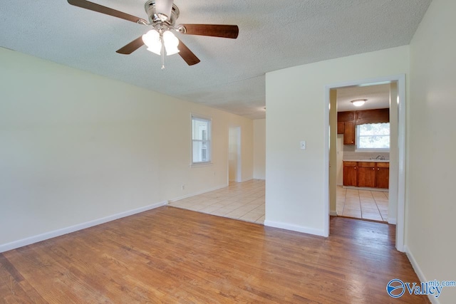 unfurnished room featuring ceiling fan, a textured ceiling, and light wood-type flooring