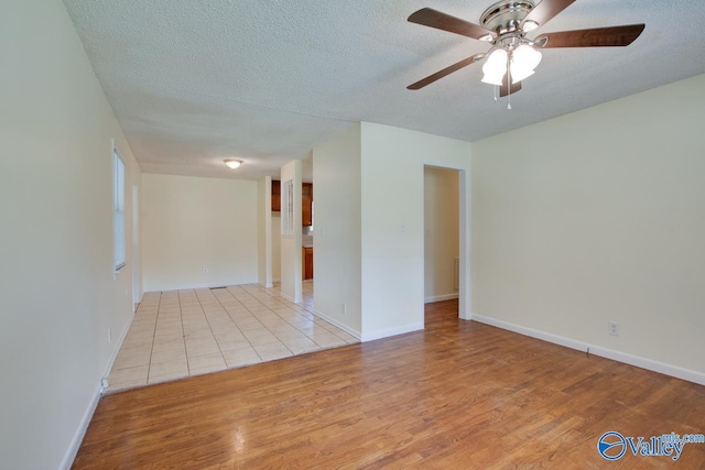 spare room with light hardwood / wood-style flooring, ceiling fan, and a textured ceiling