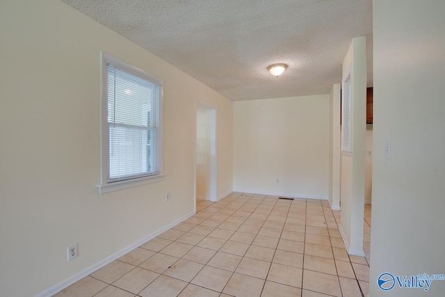 tiled empty room featuring a textured ceiling