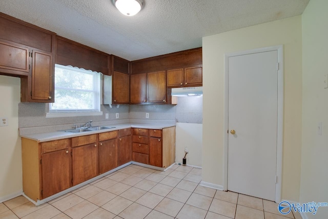 kitchen with a textured ceiling, backsplash, light tile patterned flooring, and sink