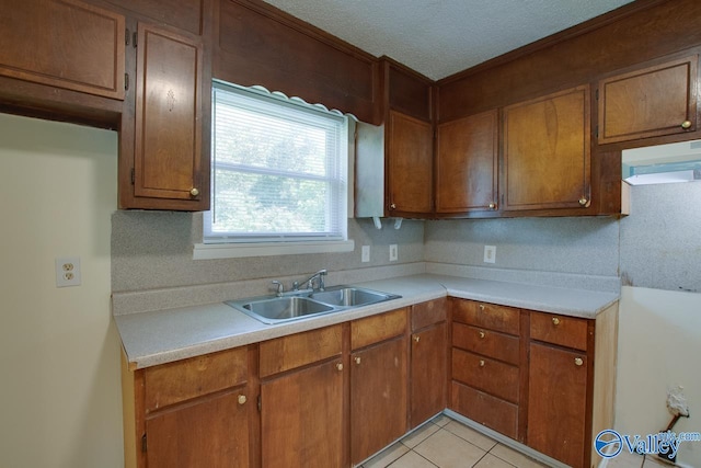 kitchen featuring a textured ceiling, sink, light tile patterned floors, and exhaust hood