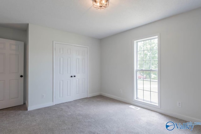 unfurnished bedroom with baseboards, visible vents, a closet, and carpet