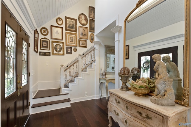 entryway with dark hardwood / wood-style flooring, vaulted ceiling, and ornate columns