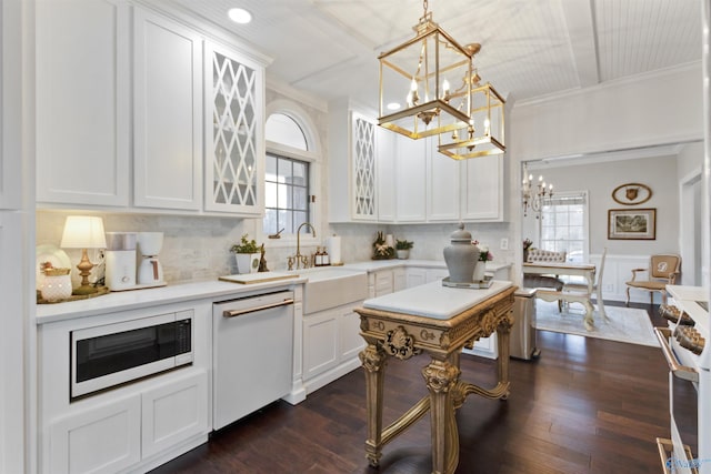 kitchen with sink, white cabinets, hanging light fixtures, a notable chandelier, and white appliances