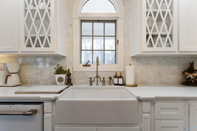 kitchen featuring tasteful backsplash, white cabinetry, dishwasher, and sink