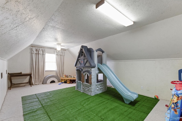 playroom featuring vaulted ceiling, carpet flooring, and a textured ceiling