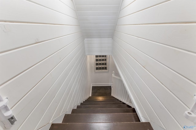 stairs featuring wood-type flooring and wood walls