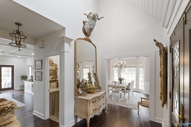 corridor with a high ceiling, a notable chandelier, and dark hardwood / wood-style flooring