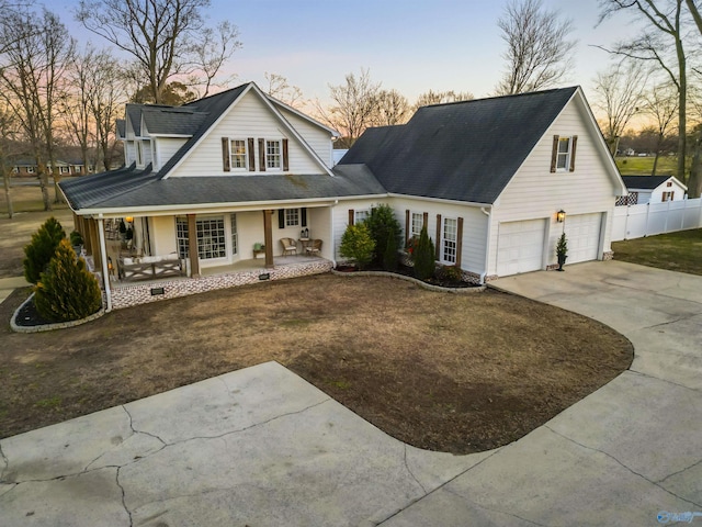 view of front of property featuring a garage, a porch, and a lawn