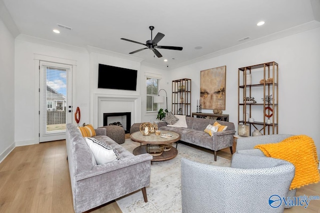 living room featuring crown molding, light wood-type flooring, and ceiling fan