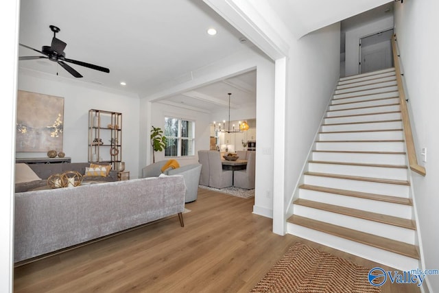 living room with ceiling fan with notable chandelier, crown molding, and hardwood / wood-style floors