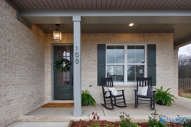 entrance to property with a porch and brick siding