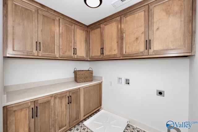 clothes washing area with electric dryer hookup, washer hookup, cabinets, and light tile patterned floors