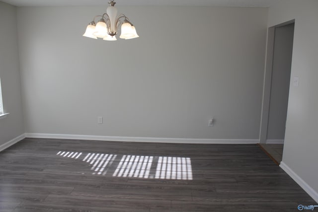 spare room featuring dark hardwood / wood-style flooring and a notable chandelier